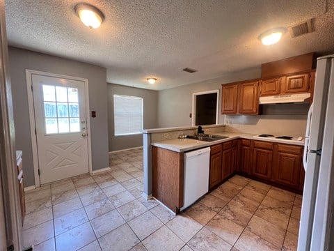 A kitchen with a white fridge and wooden cabinets.